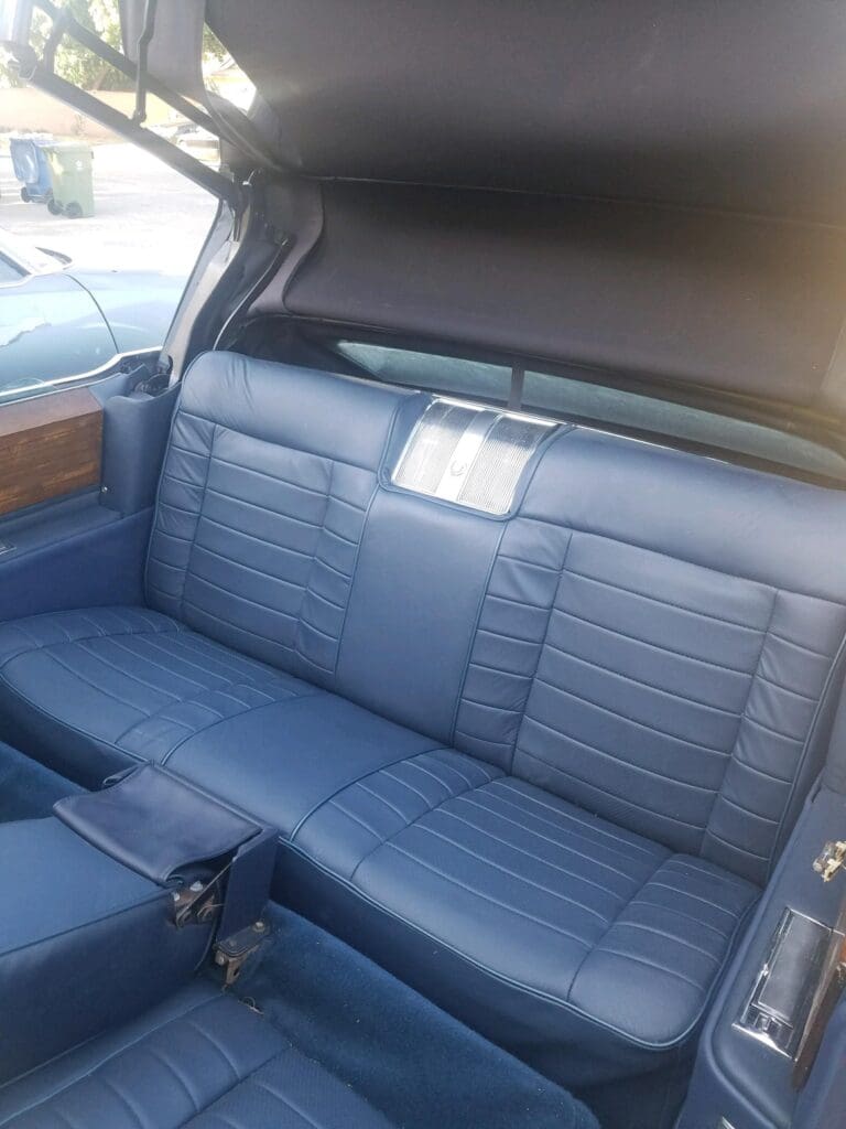 Luxurious blue leather backseat with wood trim in a classic car.
