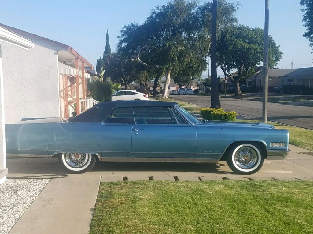 Classic blue vintage car parked by a suburban sidewalk.