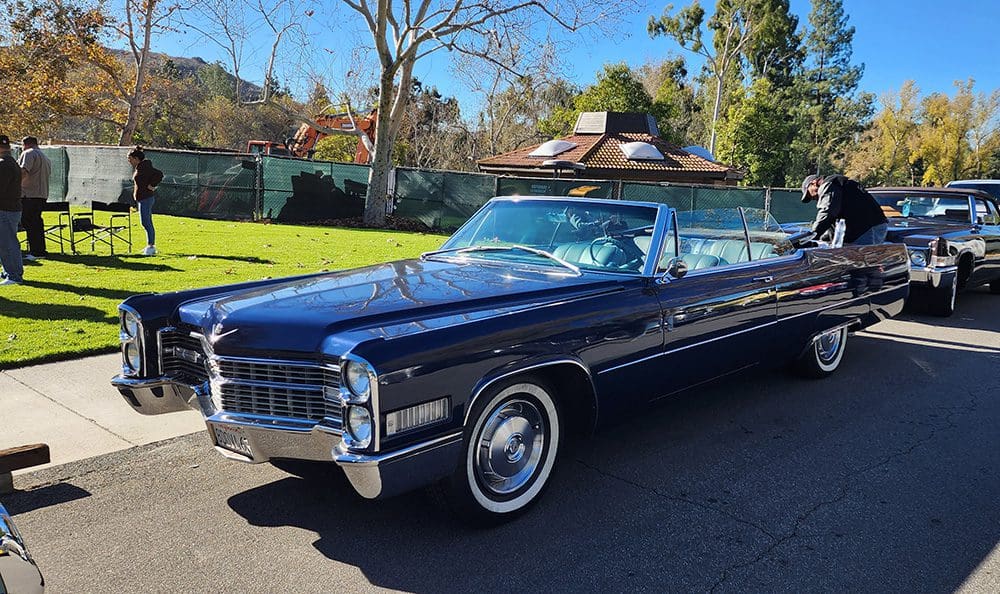 Classic black convertible car parked on a sunny street.