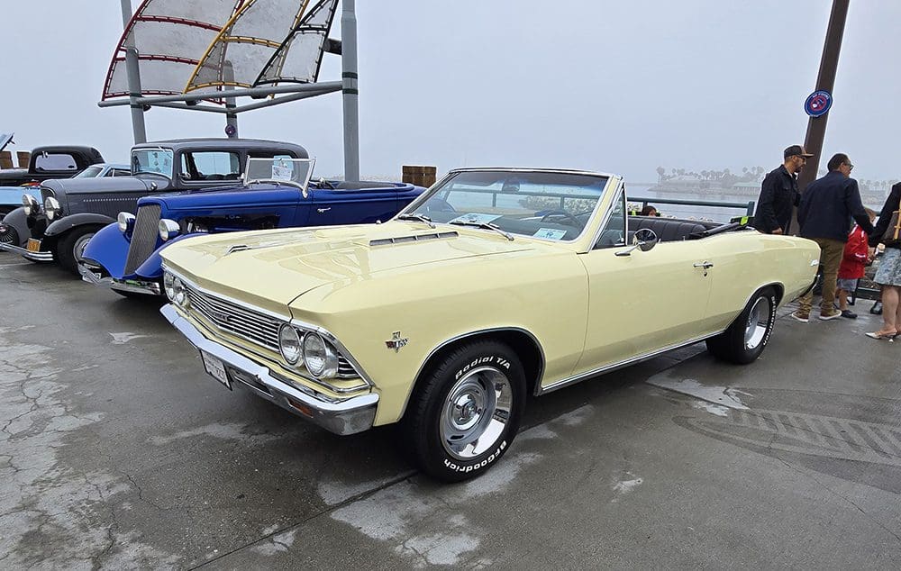 Classic yellow convertible car parked on a wet surface.