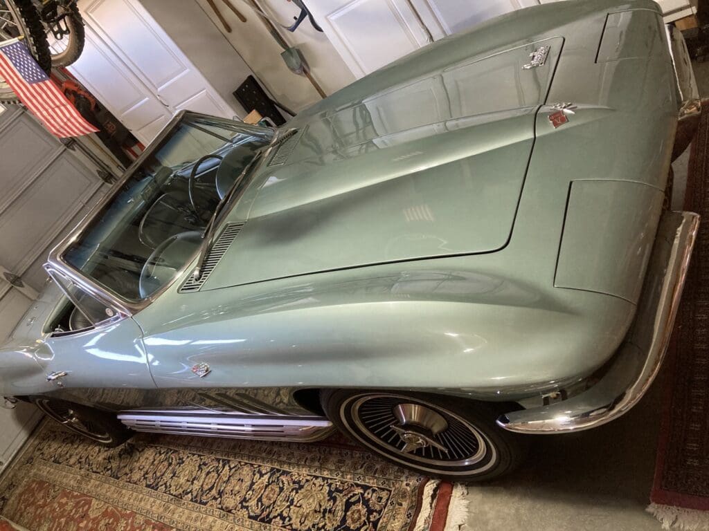 Classic silver convertible sports car parked indoors on a carpet.