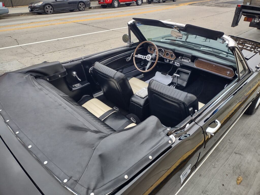 Classic convertible car interior with black seats and steering wheel.