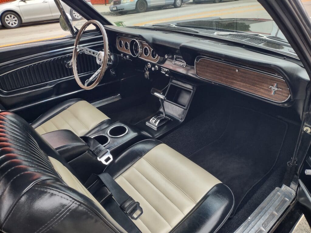 Classic car interior with wood trim and two-tone seats.