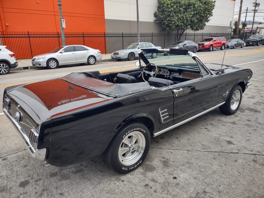 Classic black convertible car parked on a city street.