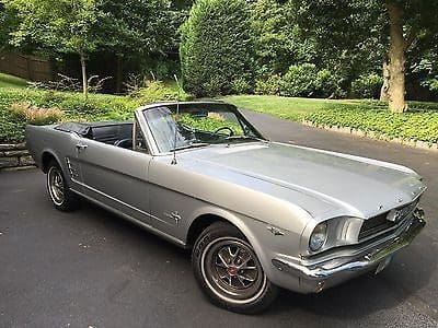 Classic silver convertible car parked outdoors on a driveway.