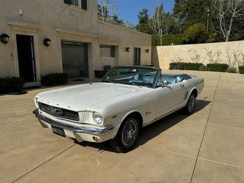 Classic white convertible car parked in a driveway on a sunny day.