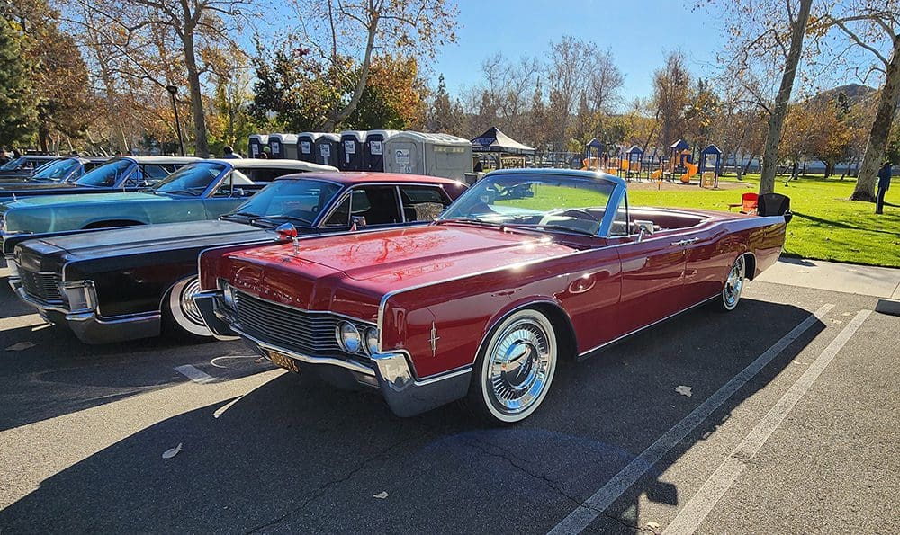 Classic red convertible car parked outdoors on a sunny day.