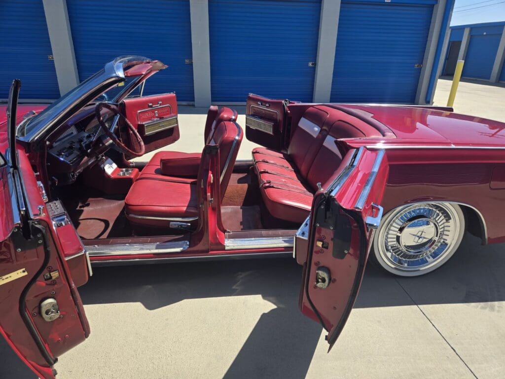 Classic red car with open doors showcasing its vintage interior and shiny exterior.