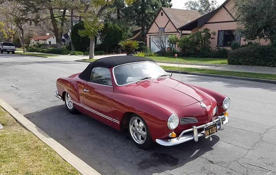 Classic red convertible parked on a sunny suburban street.
