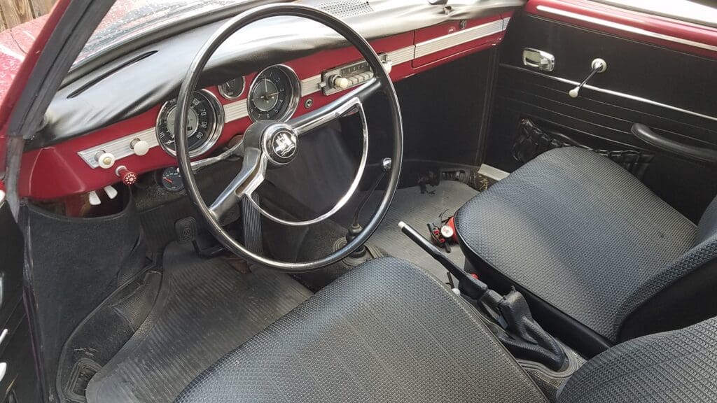 Interior view of a vintage car with a classic steering wheel and dashboard.