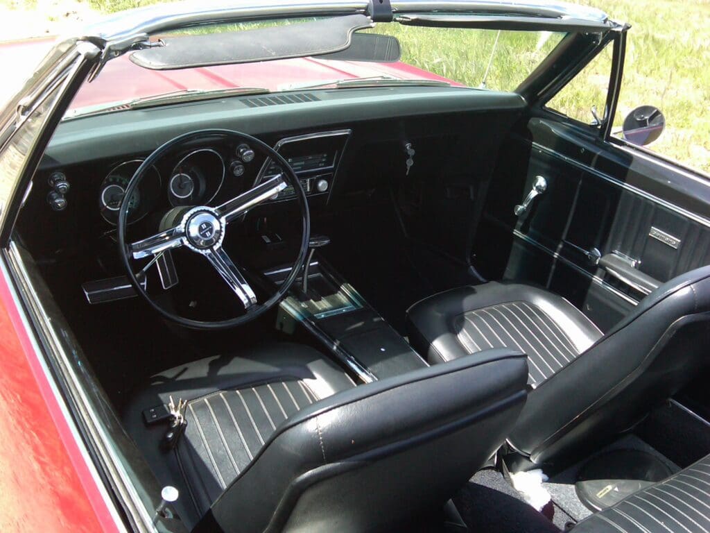 Classic car interior with black leather seats and vintage steering wheel.