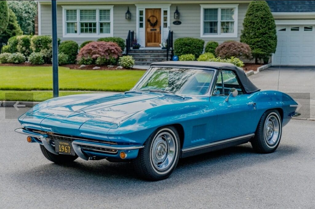 Classic blue convertible parked in front of a suburban house.