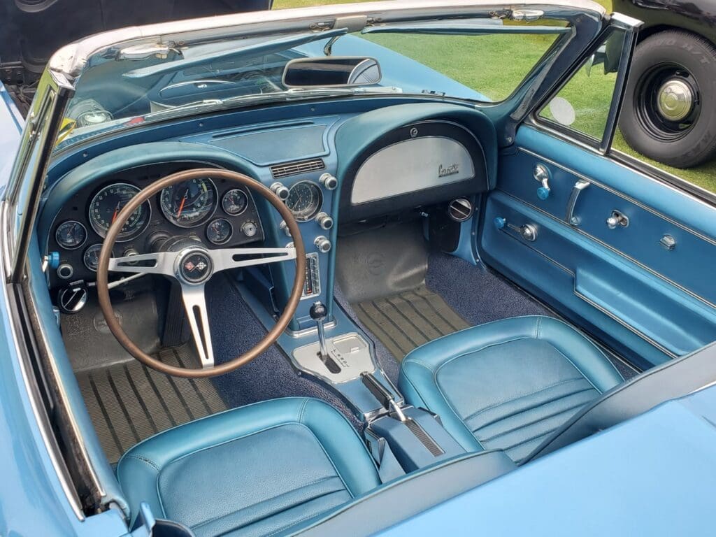 Classic blue car interior with vintage steering and seats.