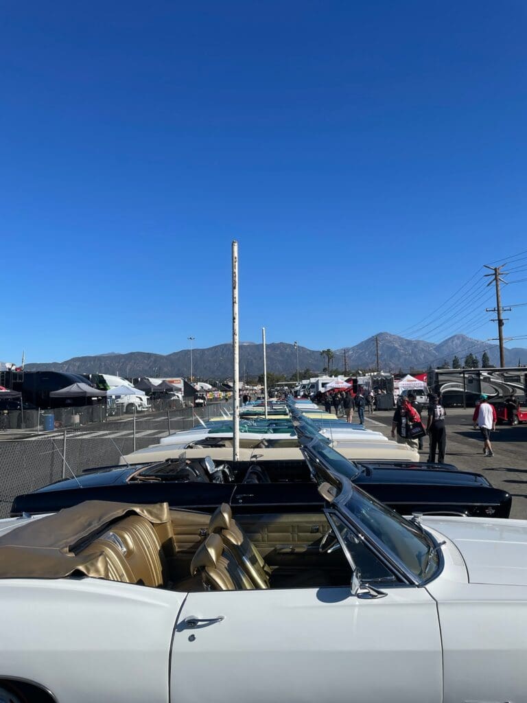 Classic convertible car parked with mountains and clear sky in the background.