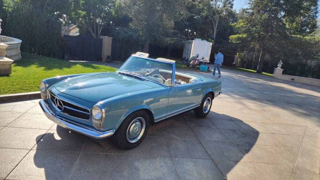 Classic light blue convertible parked in a sunny driveway.