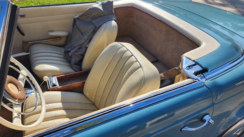 Interior of a vintage convertible car with beige leather seats.