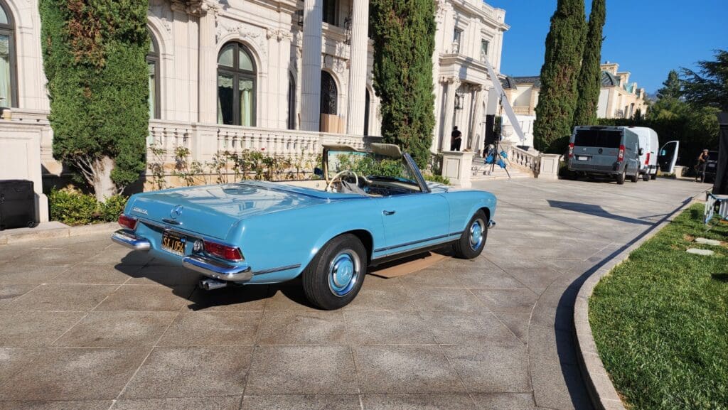 A classic blue convertible car parked near a historic building.