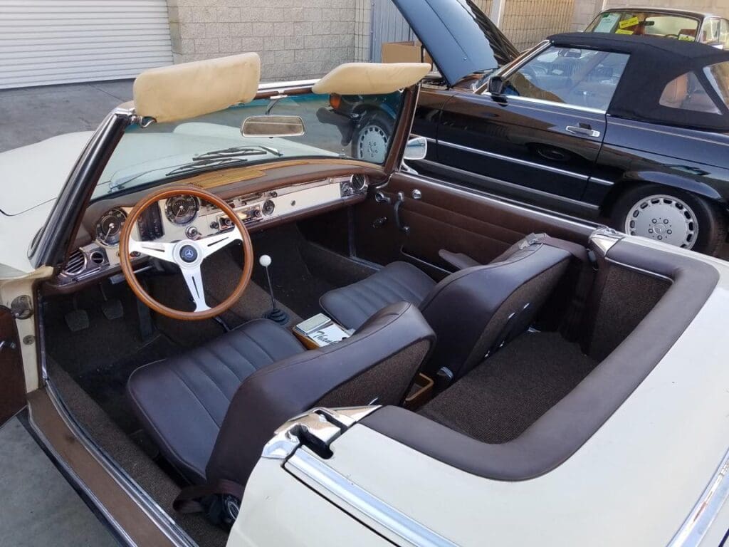 Interior of a classic convertible car with wooden dashboard and black leather seats.