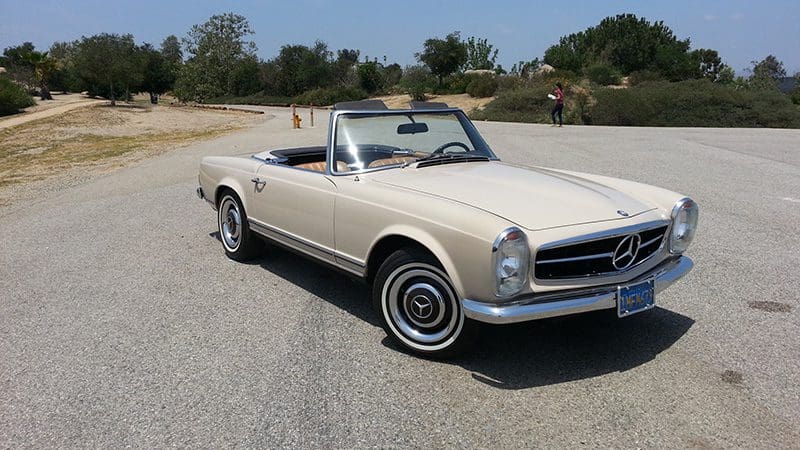 Classic beige convertible car parked on a sunny road.