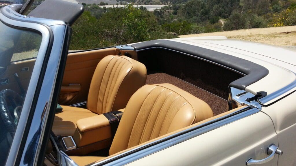Interior of a vintage convertible car with tan leather seats.