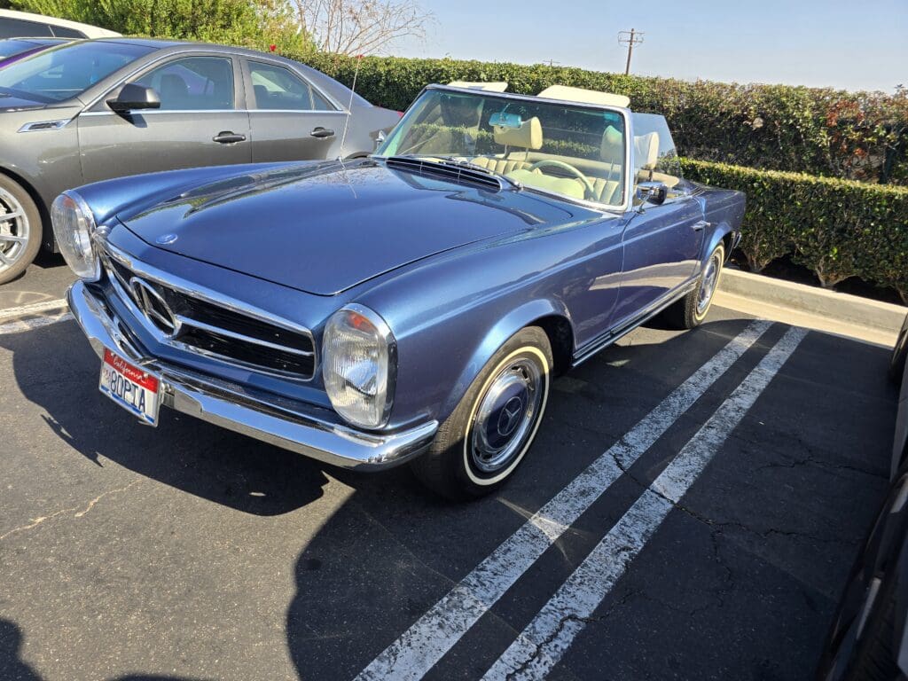 Classic blue convertible Mercedes-Benz parked outdoors under sunlight.