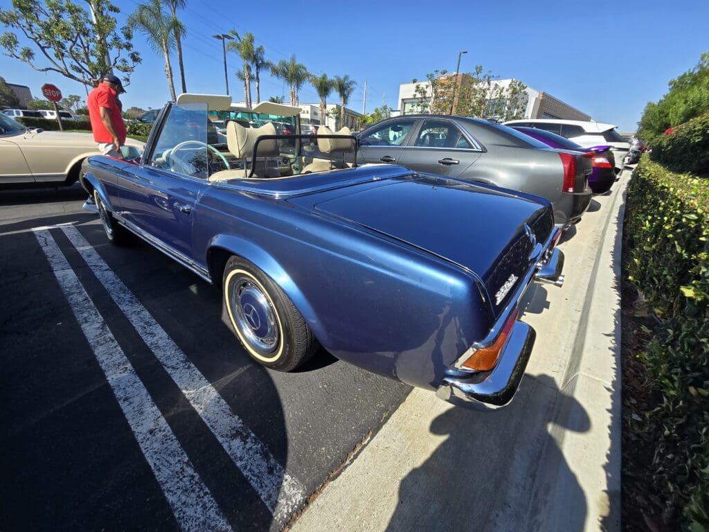 Classic blue convertible car parked with palm trees in the background.