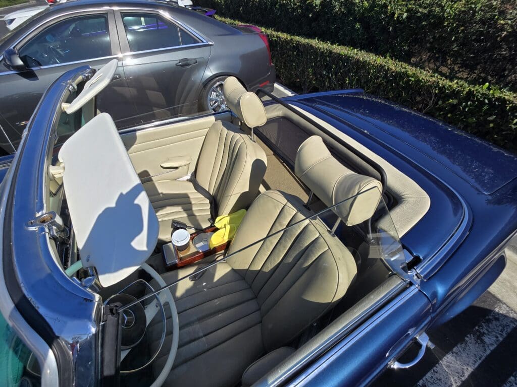 Classic convertible car with beige leather seats and an open roof.