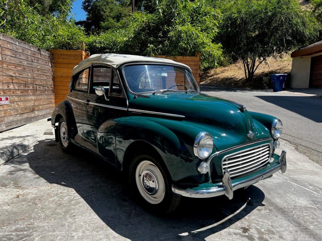 Classic green Morris Minor car parked outdoors on a sunny day.