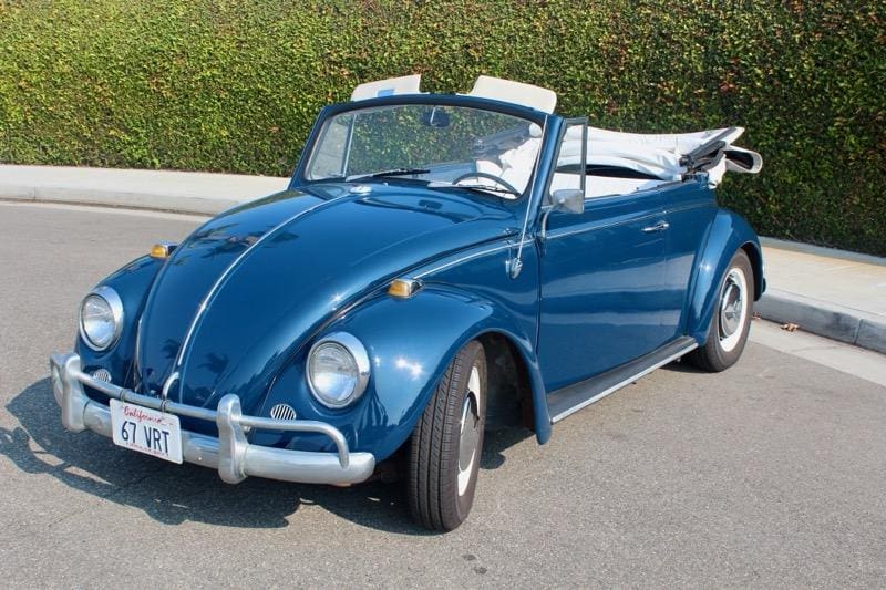 Classic blue Volkswagen Beetle convertible parked outdoors.