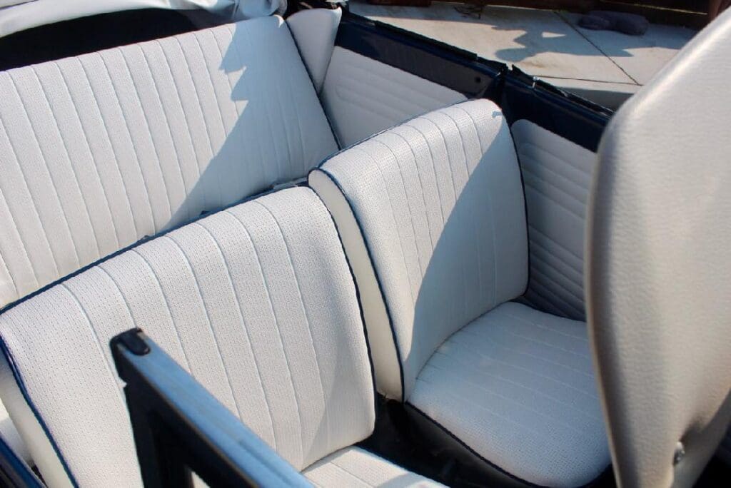 Close-up of vintage car's cream leather seats with stitching detail.