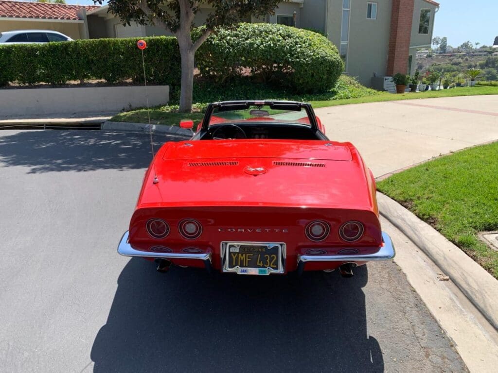Red vintage convertible car parked on a sunny street.