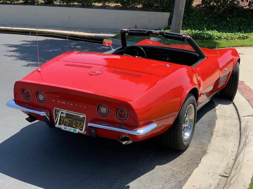 Red vintage convertible car parked on a sunny street.