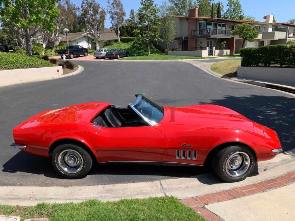 Classic red convertible sports car parked on a suburban street.