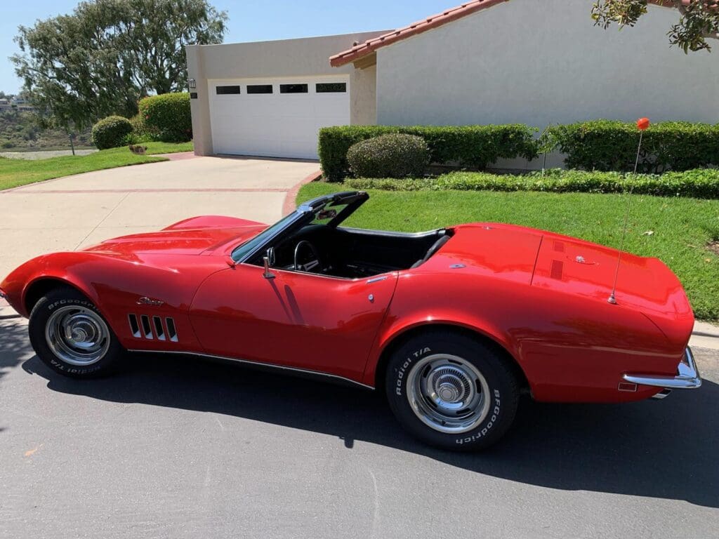 Red vintage convertible car parked on a driveway in front of a house.