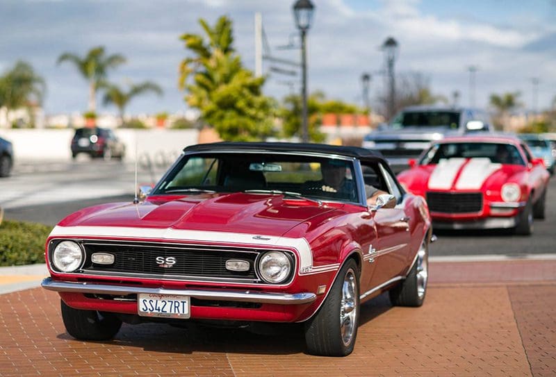 A classic red muscle car parked outdoors on a sunny day.