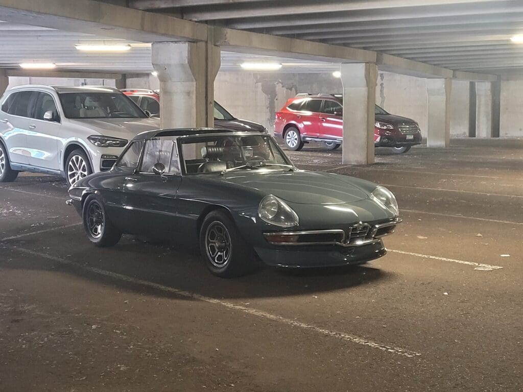 Classic dark green convertible parked in an indoor garage.