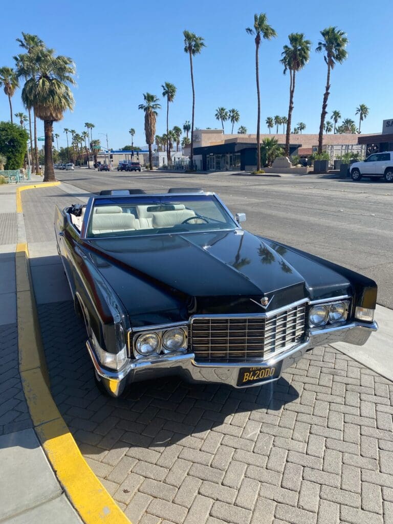 Classic black convertible car parked on a sunny street.