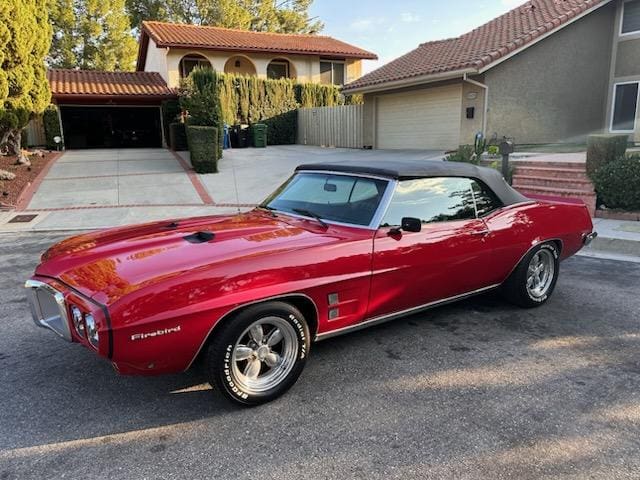 Red classic convertible car parked in front of a house.