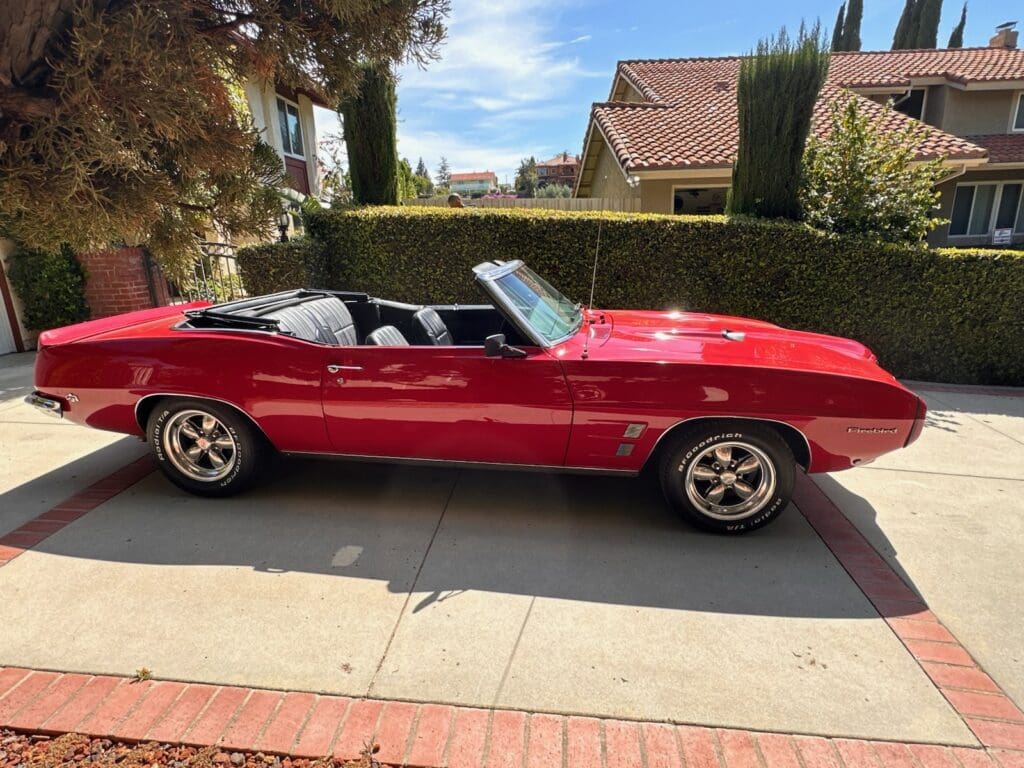 Red classic convertible car parked on a sunny driveway.