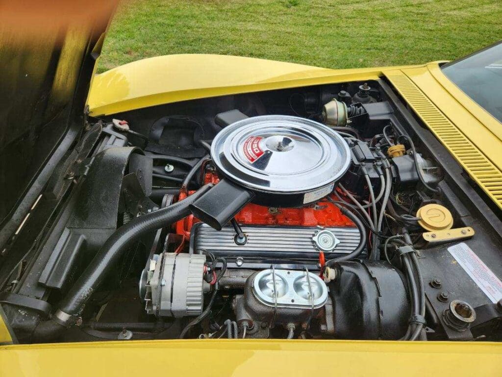 Classic car engine with polished components and yellow exterior.