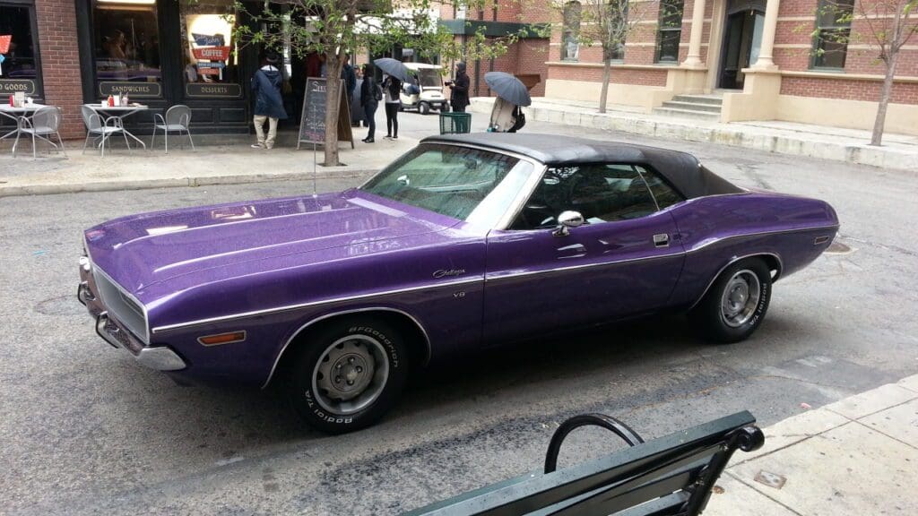 Classic purple convertible car parked on a city street.