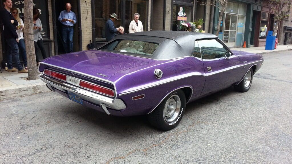 Classic purple convertible car parked on a city street.