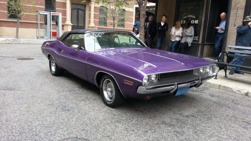 Classic purple muscle car parked on a city street.