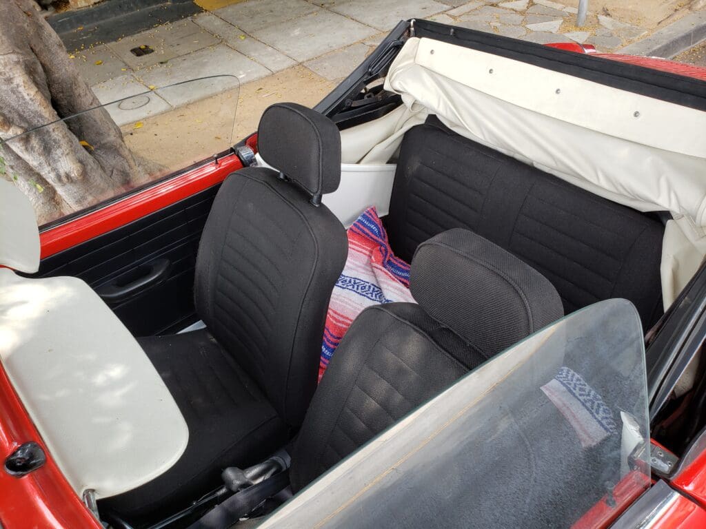 Interior of a convertible car with black seats and a red exterior.