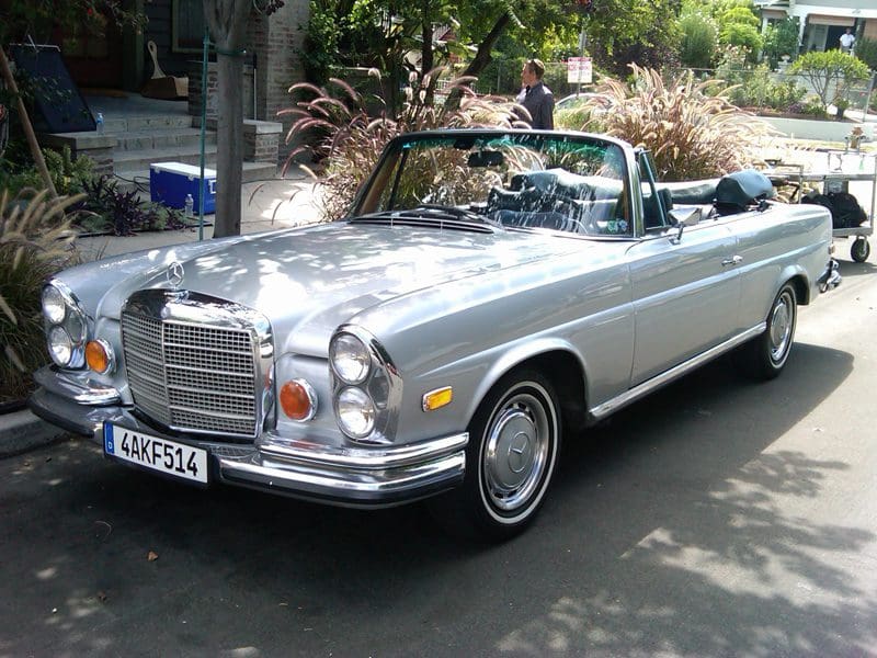 Classic silver convertible car parked on a street.