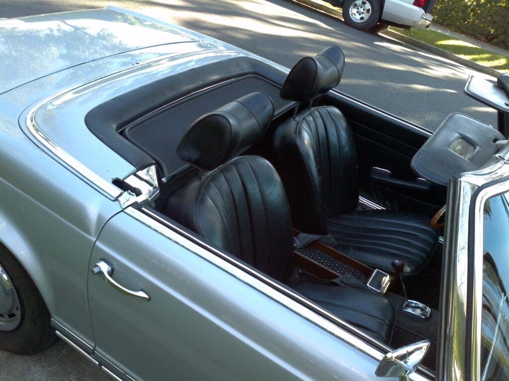 Close-up of a classic car's black leather interior with bucket seats.