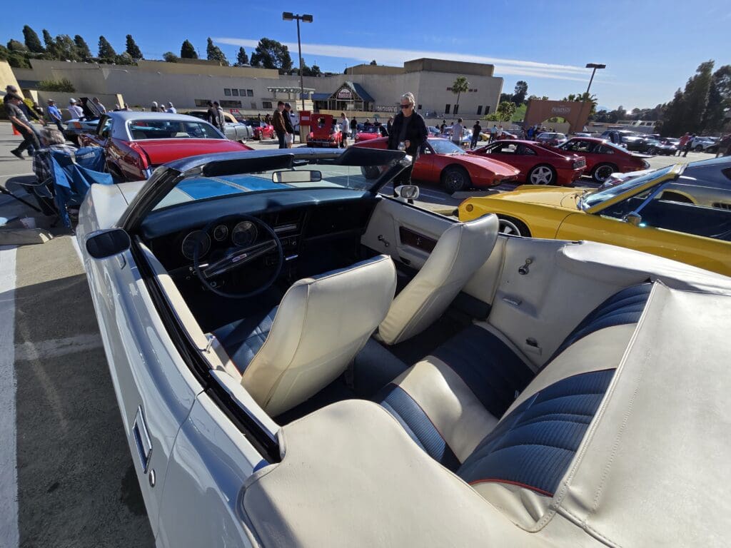 Classic white convertible with beige leather interior at a car show.