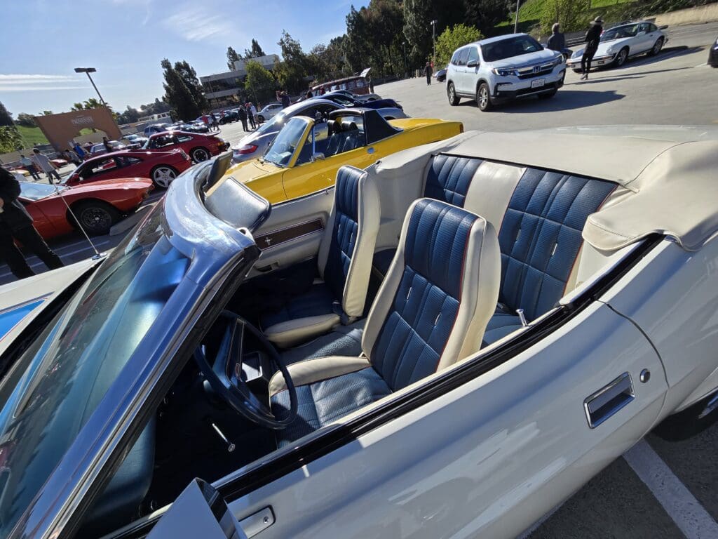 Convertible car with blue and white interior parked among other vehicles.