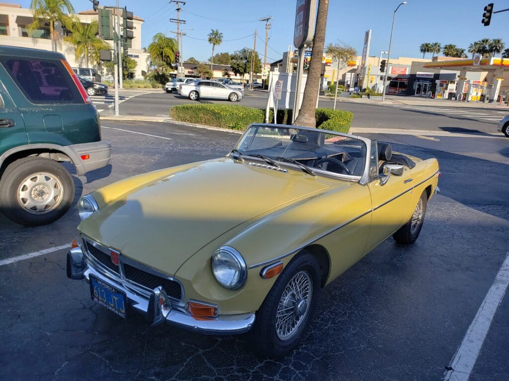 Yellow vintage convertible car parked outdoors on a sunny day.