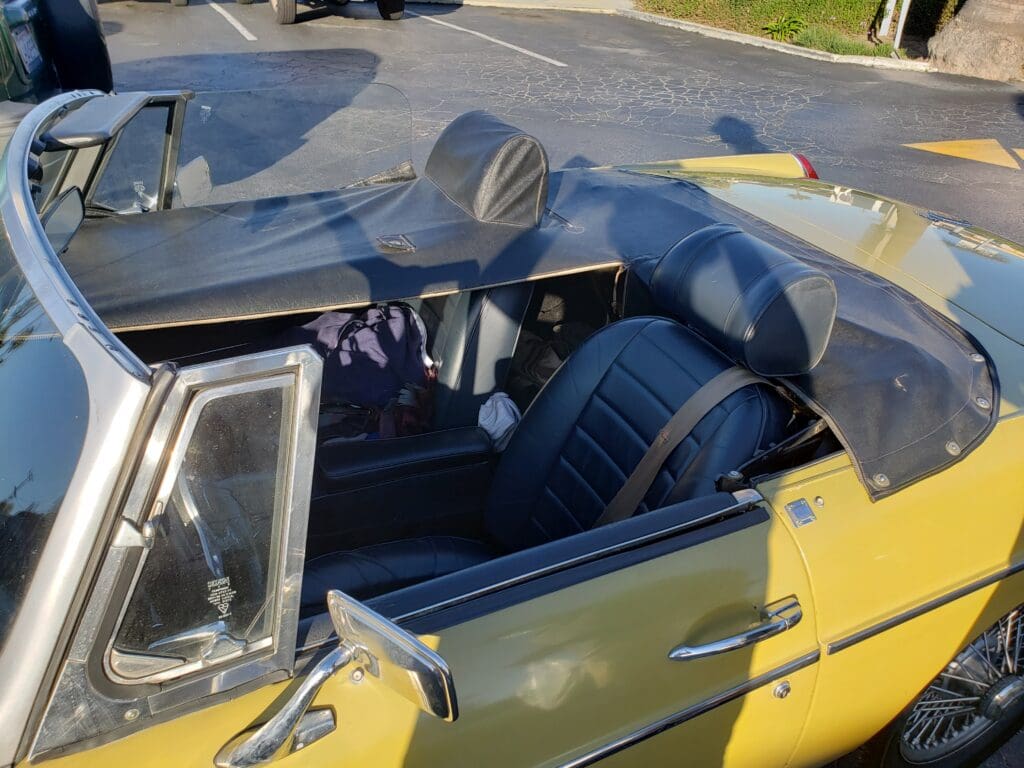 Classic yellow convertible car with black interior seats parked outdoors.